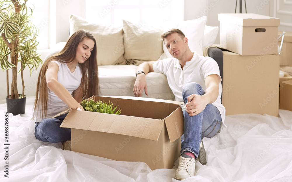 Portrait of happy couple looking at laptop computer together sitting in new house, surrounded with boxes Portrait of happy couple looking at laptop computer together sitting in new house, surrounded with boxes