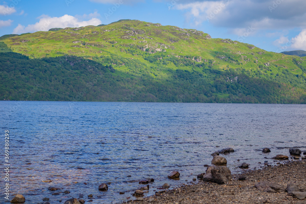 The lake shore view of Loch Lomond in Scotland, in summer time, on a sunny day.