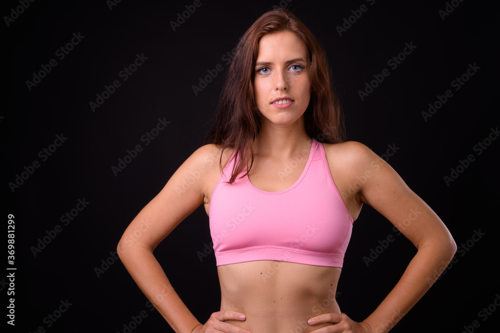 Young beautiful woman ready for gym against black background Young beautiful woman ready for gym against black background