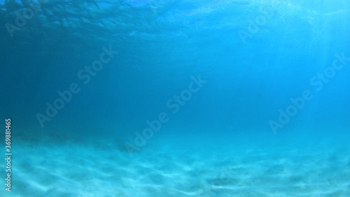 Obraz na plátne Underwater background of blue sea water and ocean floor