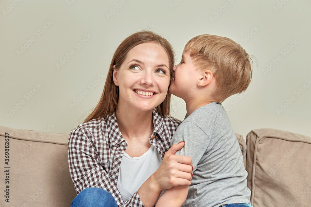 Little boy son kisses his happy smiling mother on the cheek. A loving family. Little boy son kisses his happy smiling mother on the cheek. A loving family.