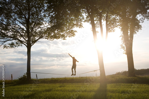 Tableau sur toile junger Mann in Balance auf der Slackline im Sonnenuntergang