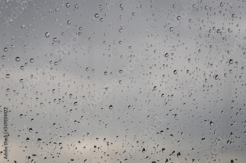 water rain drops on glass surface window with cloudy background. Copy space. Natural Pattern.