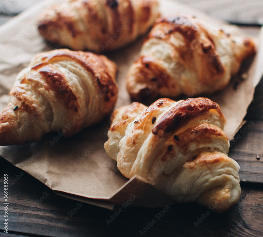 Freshly baked homemade croissants on wooden table, selective focus Fresh out of the oven. Breakfast or brunch concept.