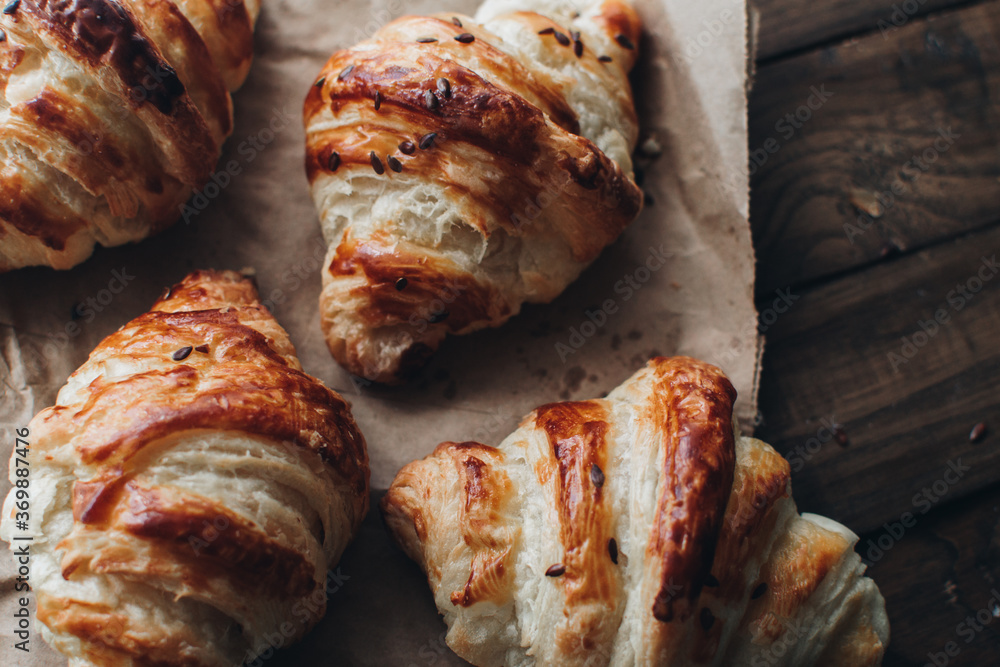Freshly baked homemade croissants on wooden table, selective focus Fresh out of the oven. Breakfast or brunch concept.