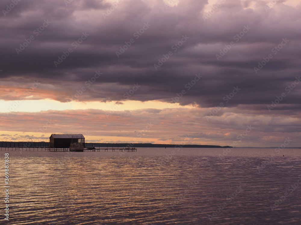 Sunset, summer, beautiful clouds at sunset. Thunderous sunset. Pier on the big Kama river. Ural, Russia, Perm Territory, Elovo.