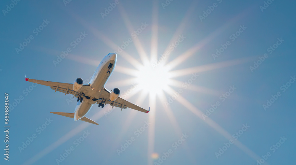 Naklejka premium Comercial airplane take off from airport runway against the backdrop of a scenic evening sky with sun rays.