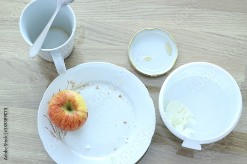 Apple, desk, and porcelain dish on the table.