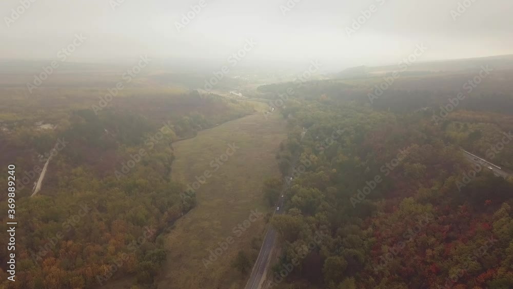 Aerial view of a forest road, Road along the hill with fog, Cinematic drone shot flying over a autumn landscape. Aerial view of a forest road, Road along the hill with fog, Cinematic drone shot flying over a autumn landscape.