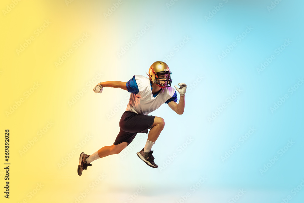 High jump. American football player isolated on gradient studio background in neon light. Professional sportsman during game playing in action and motion. Concept of sport, movement, achievements.