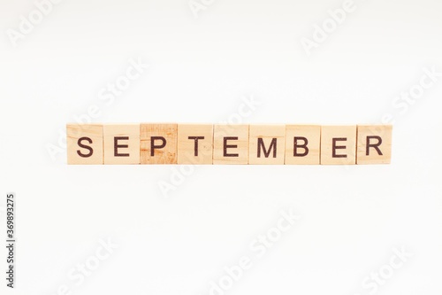 Word SEPTEMBER made of wooden blocks on white background. Month of year. First month of autumn