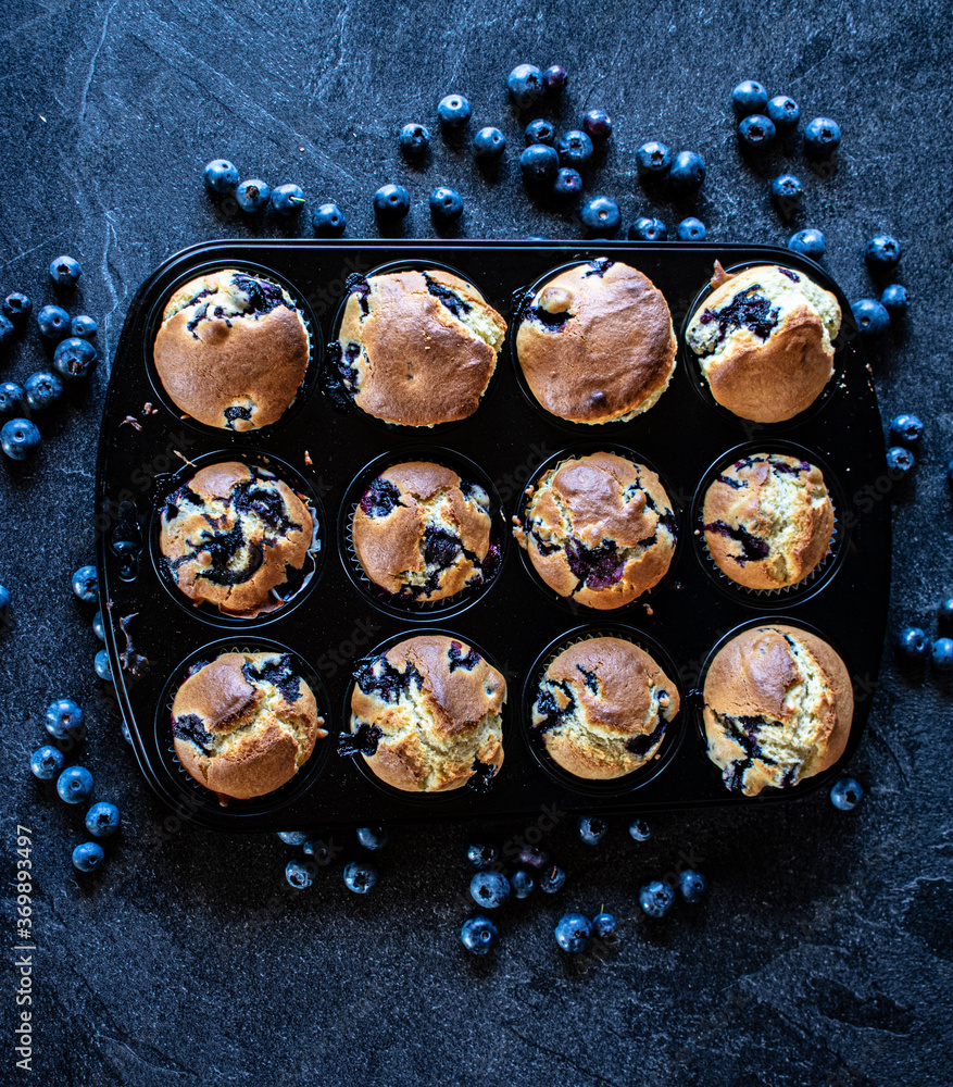 Blueberry muffins in a muffin tin on dark background Blueberry muffins in a muffin tin on dark background