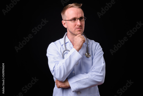 Handsome man doctor with blonde hair against black background