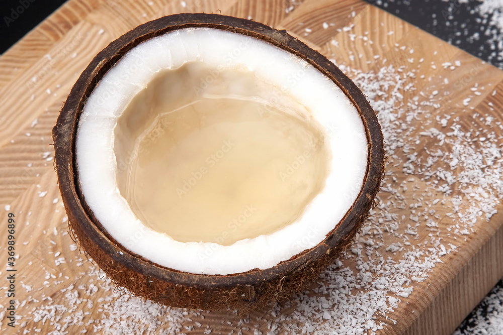 cut fresh coconut with real coconut milk on background of coconut flakes. vitamin fruits. healthy food