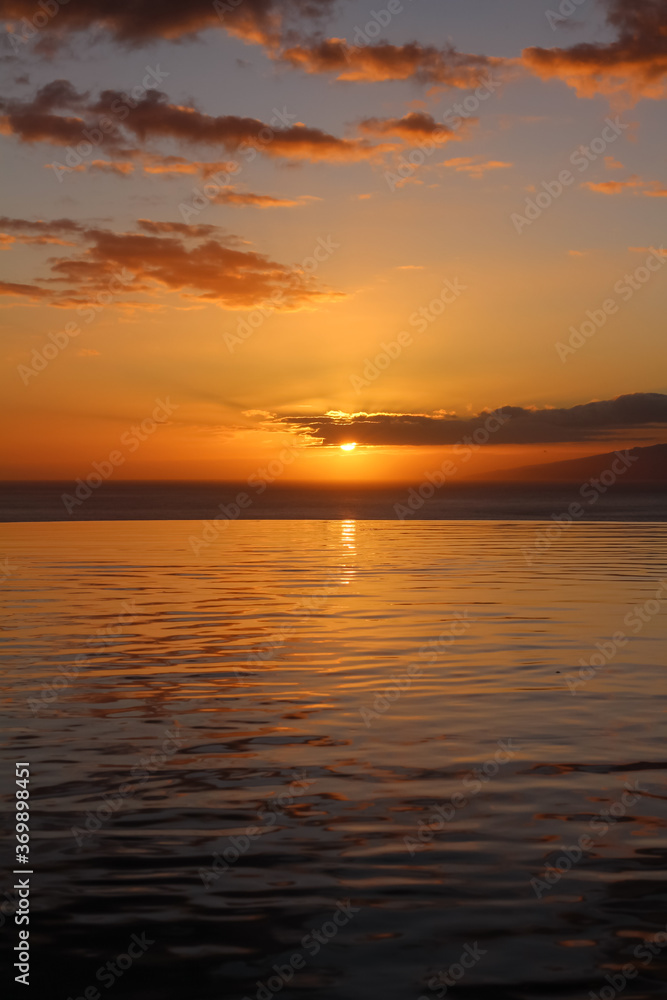 Sunset on the atlantic ocean. Swimming pool on the background of the sun setting in the ocean.