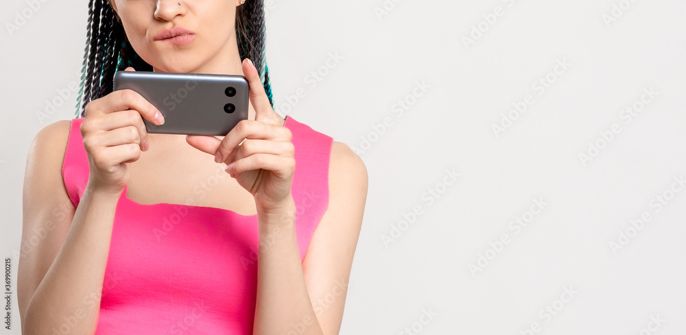 Z generation lifestyle. Bored woman in pink with braids hairstyle using smartphone isolated on white copy space. Online entertainment. Information technology. Mobile app. Social networking. Z generation lifestyle. Bored woman in pink with braids hairstyle using smartphone isolated on white copy space. Online entertainment. Information technology. Mobile app. Social networking.