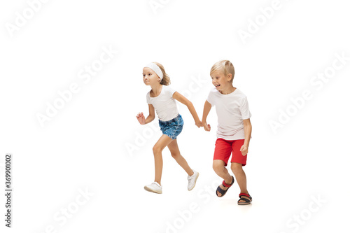 Fun. Happy kids, little emotional caucasian boy and girl jumping and running isolated on white background. Look happy, cheerful, sincere. Copyspace for ad. Childhood, education, happiness concept.