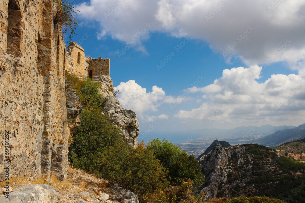 Stone towers of the castle of Saint Hilarion against a blue sky with clouds. The mountains of Cyprus and the view down to Kyrenia and the Mediterranean sea. Cyprus.