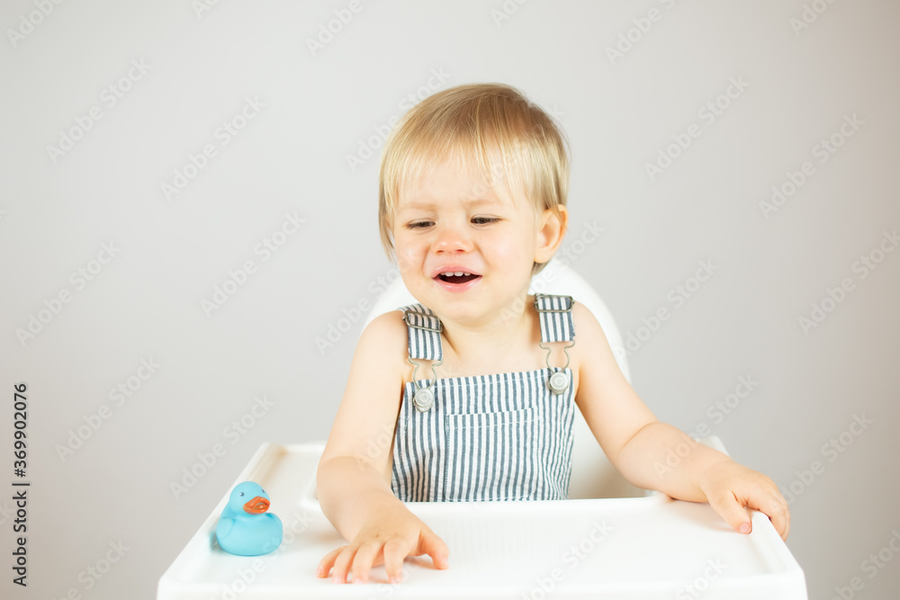 Blond baby with striped overalls sitting and angry Blond baby with striped overalls sitting and angry