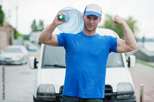 Delivery muscular man in front cargo van delivering bottles of water.