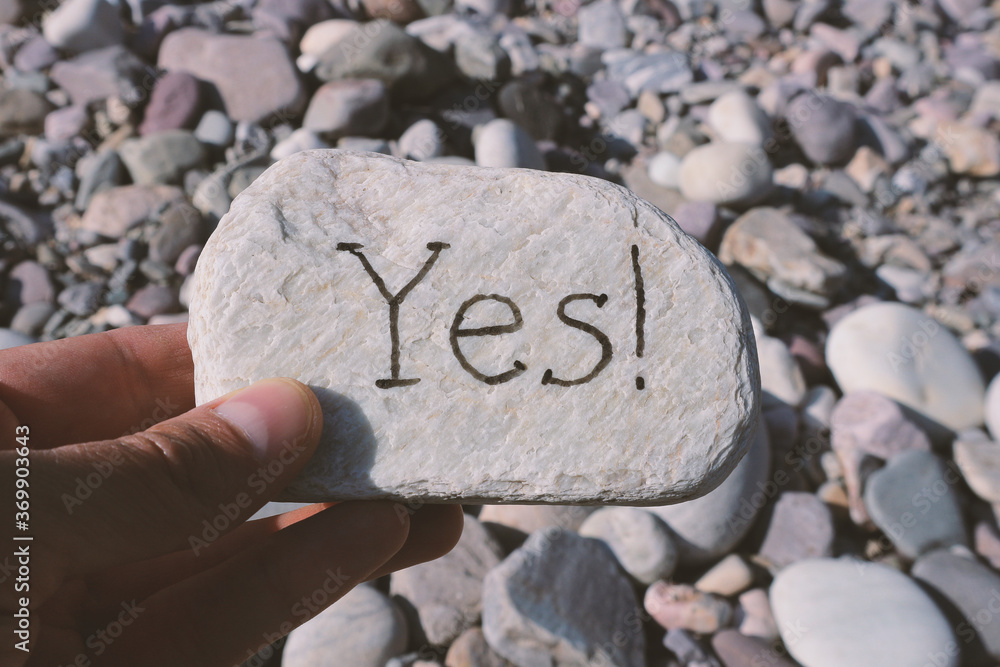 A hand is holding a flat stone with the word A hand is holding a flat stone with the word