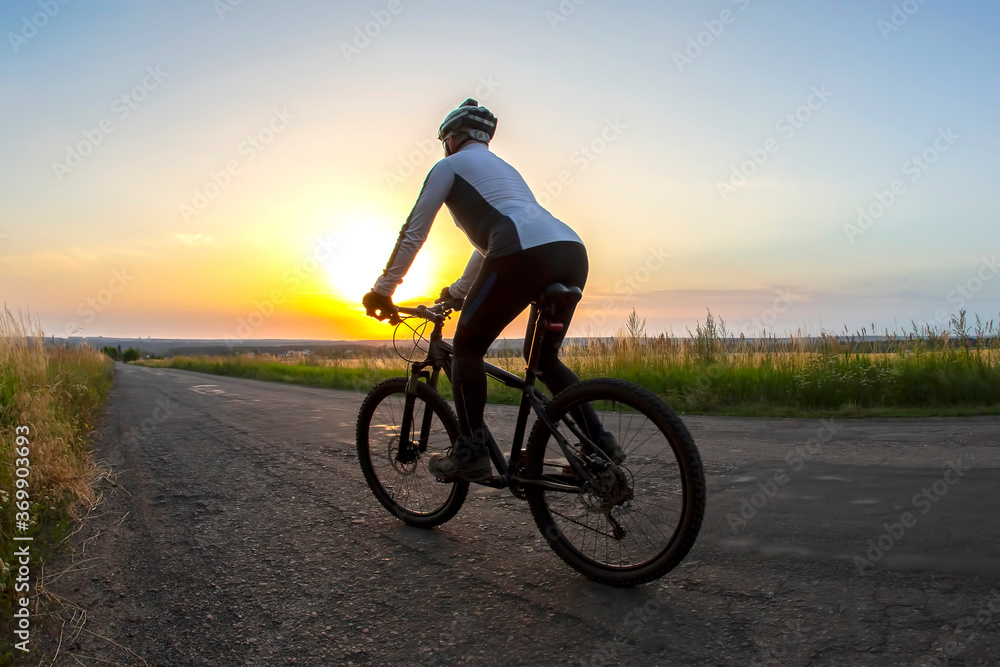 cyclist rides on the road into the sunset. sports and hobbies. outdoor activities cyclist rides on the road into the sunset. sports and hobbies. outdoor activities