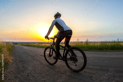 cyclist rides on the road into the sunset. sports and hobbies. outdoor activities