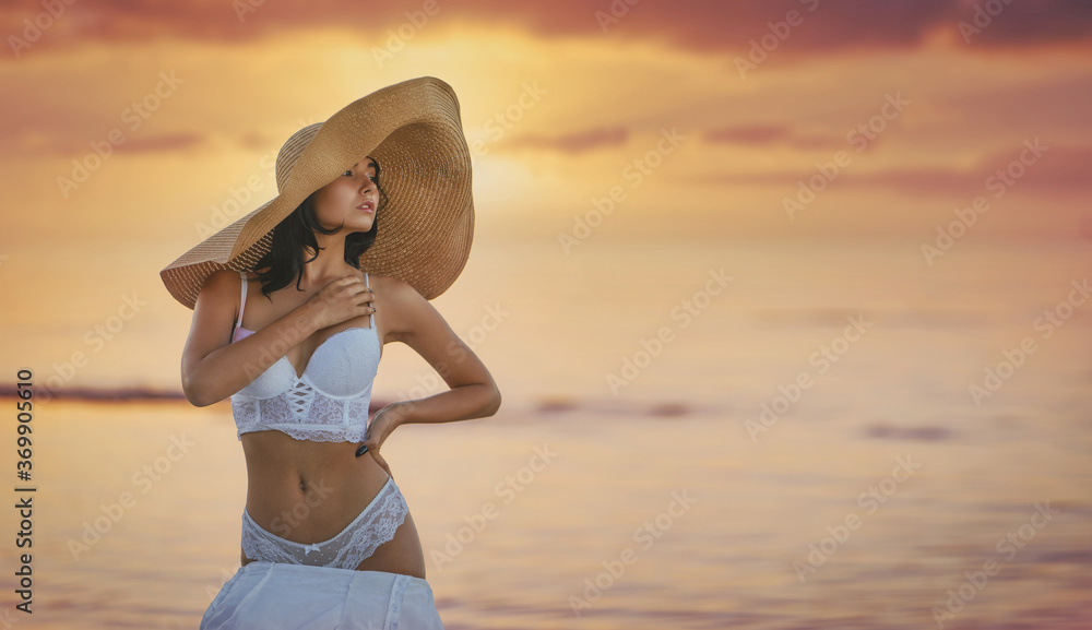 Young beautiful sexy seductive female model pose in white bridal lingerie and big beach hat on the beach Young beautiful sexy seductive female model pose in white bridal lingerie and big beach hat on the beach