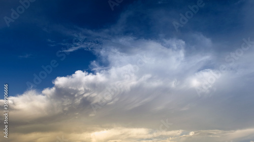 Blue sky with curve white clouds and yellow sunlight.