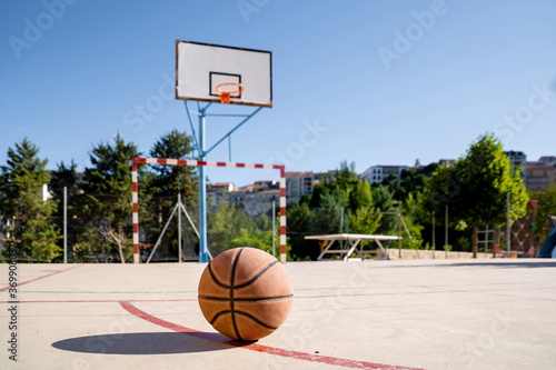 Basketball ball on a basketball court with the basket in the background
