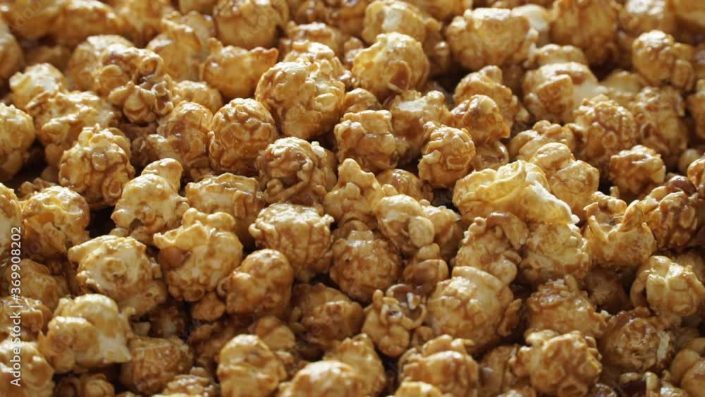 Close up of golden sweet caramel popcorn rotates on board. Crispy snack for watching movie. Food dessert background Close up of golden sweet caramel popcorn rotates on board. Crispy snack for watching movie. Food dessert background