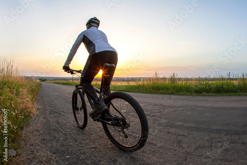 cyclist rides on the road into the sunset. sports and hobbies. outdoor activities