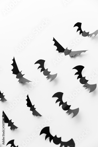halloween, decoration and scary concept - flock of black paper bats flying over white background © Syda Productions