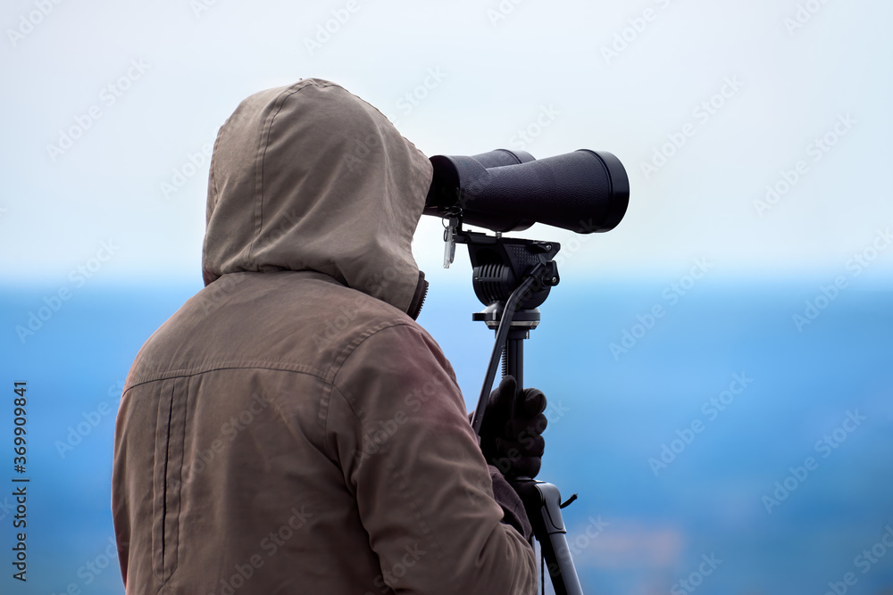 Man looking through binoculars, Massachusetts, USA