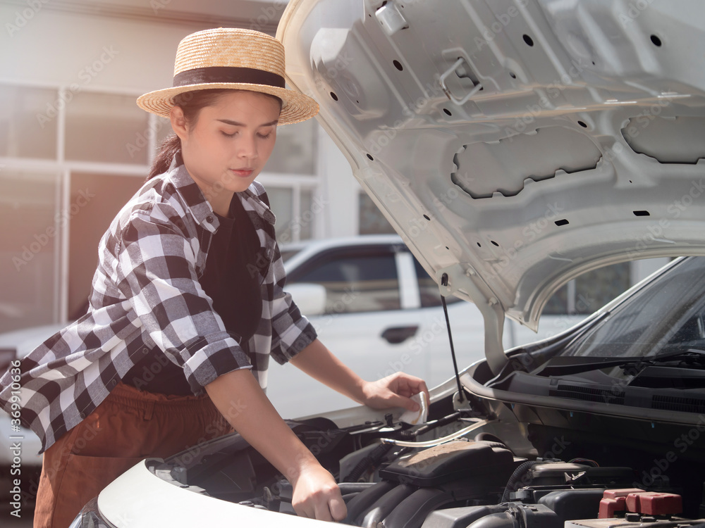 Asian woman is checking oil level in car engine. Asian woman is checking oil level in car engine.