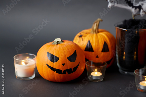 halloween and holiday decorations concept - jack-o-lanterns or carved pumpkins and burning candles