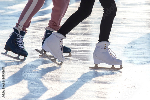 feet of different people skating on the ice rink. hobbies and leisure. winter sports