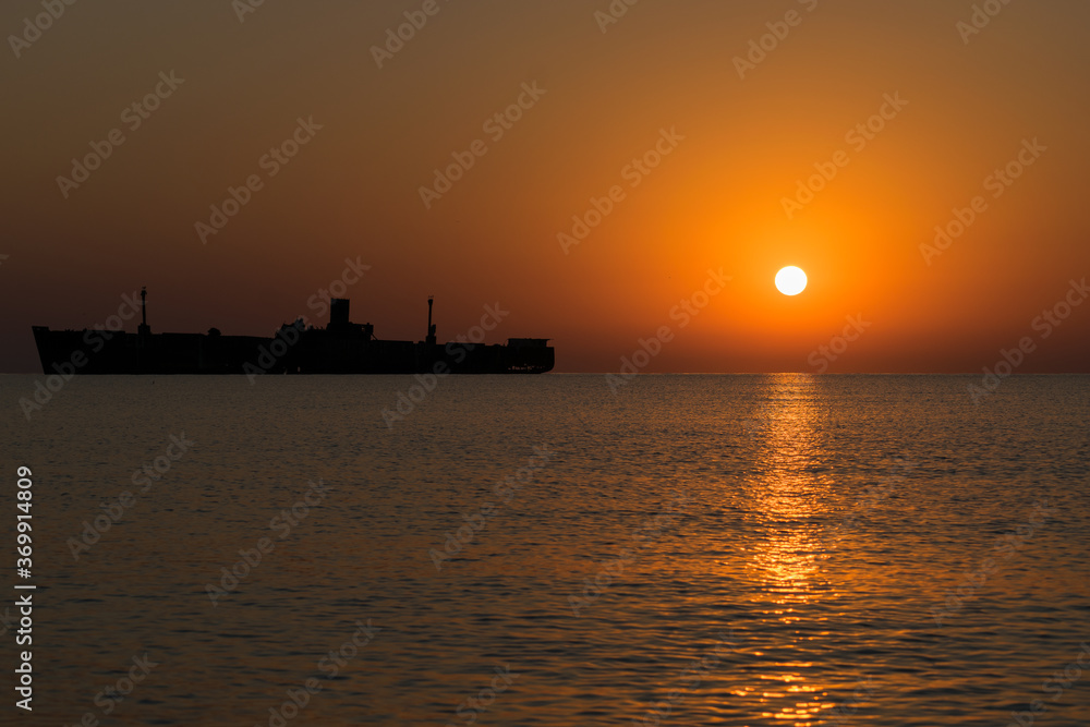 Beautiful sunrise at sea. The silhouette of an abandoned wreck in the sea