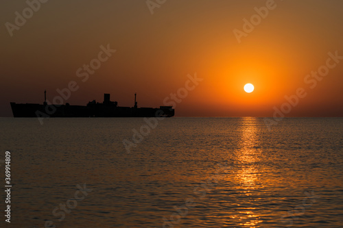 Beautiful sunrise at sea. The silhouette of an abandoned wreck in the sea © bogdan vacarciuc