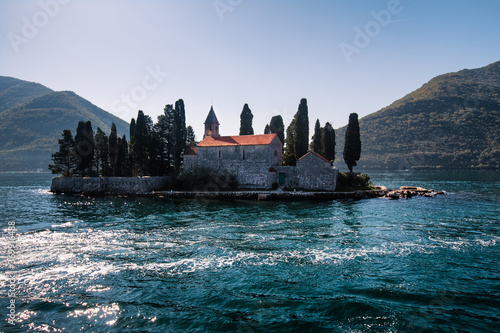 Obraz na płótnie Catholic red roof medieval monastery, bell tower, masonry wall and cypress trees on an island in the Adriatic Sea. Little island in blue water of Kotor bay among Montenegro mountains. Island panorama w salonie