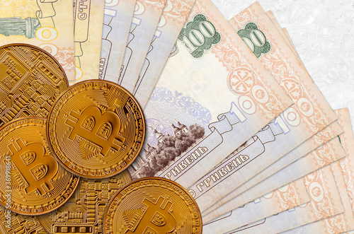 100 Ukrainian hryvnias bills and golden bitcoins. Cryptocurrency investment concept. Crypto mining or trading photo