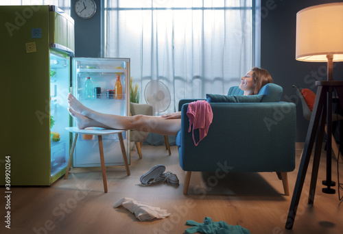 Woman cooling herself in front of the open fridge photo