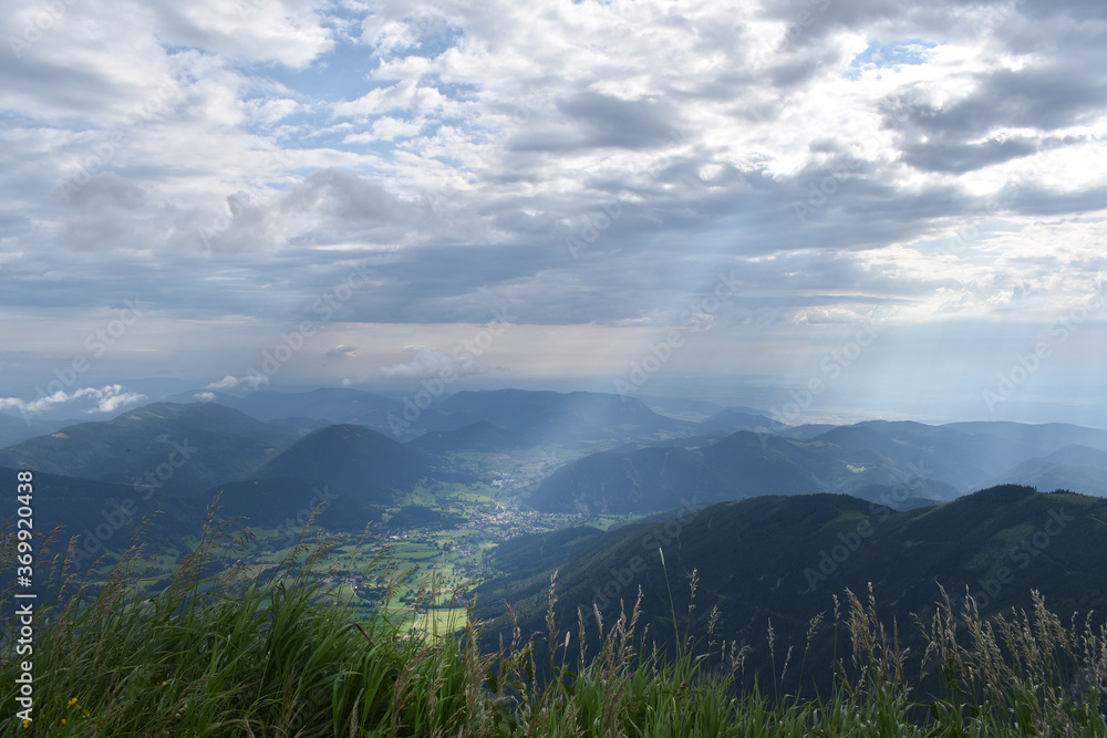 Fototapeta premium Sonnenstrahl durch dunkle Wolken im Gebirge, Sonne und Wolken in den Bergen, Berge bis zum Horizont, Erkenntnis und Inspiration 