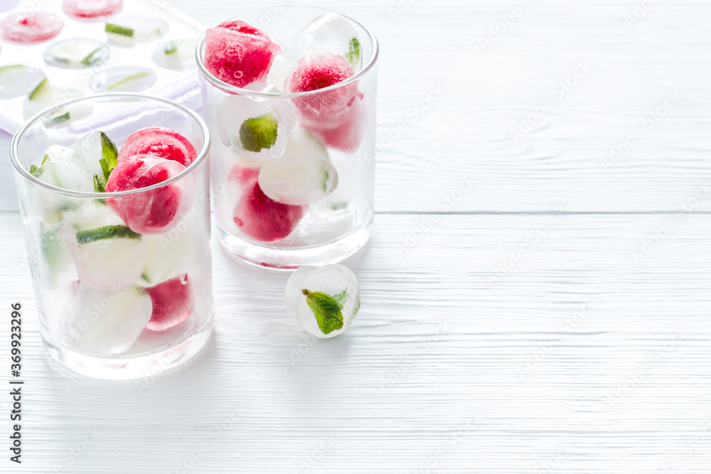 Cocktail glasses with berries in ice cubes on white table copy space