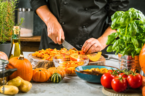 partial view of chef chopping fresh organic pumpkins