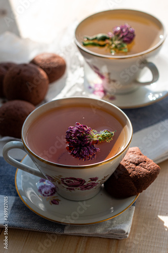 delicious tea with clover in a beautiful white set with pink flowers and a saucer with brown cookies