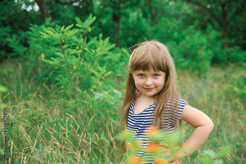 Portrait of a little girl on a natural green background. The background is blurred.