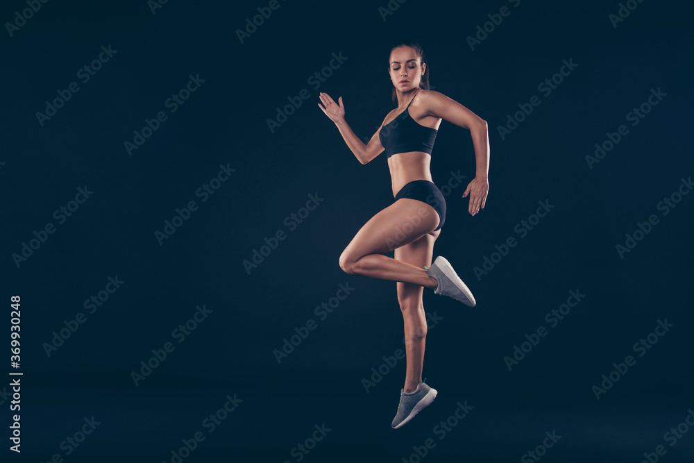 Full size profile photo short sport suit lady practicing warm up before sprint run jogging isolated black background Full size profile photo short sport suit lady practicing warm up before sprint run jogging isolated black background