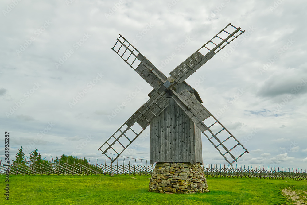 Old vintage wooden windmill in the background of the cloudy sky. Saaremaa, Estonia.