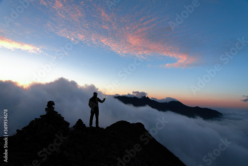 man on top of the mountain with clouds below against the background of the evening sky © Ambartsumian